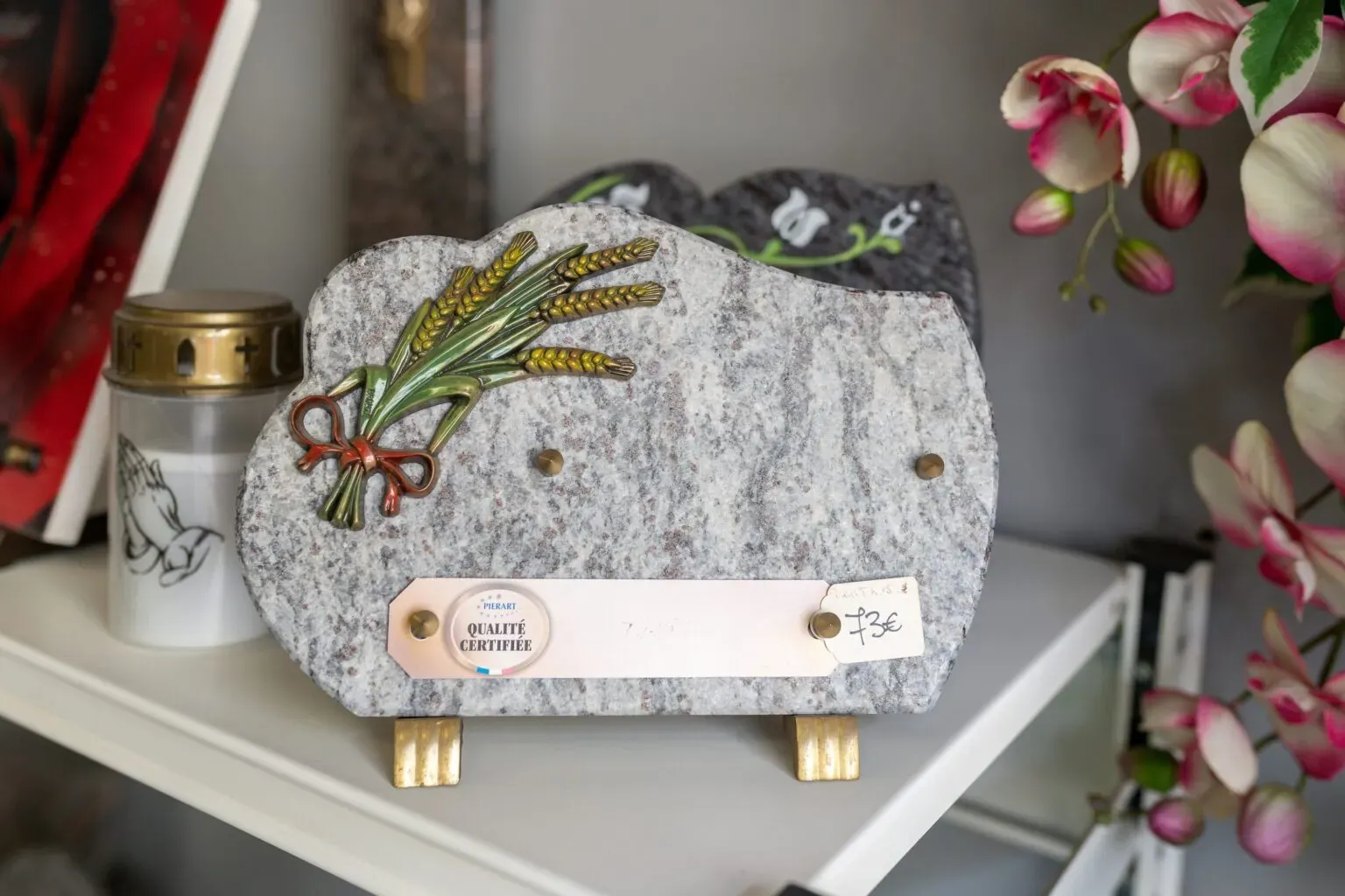 Plaque mortuaire en granit clair ornée d'un bouquet d'épis de blé.