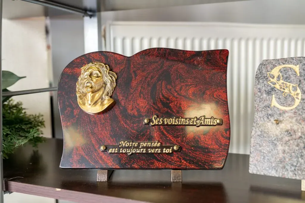 Plaque funéraire personnalisée en granit bordeaux avec éléments dorés.