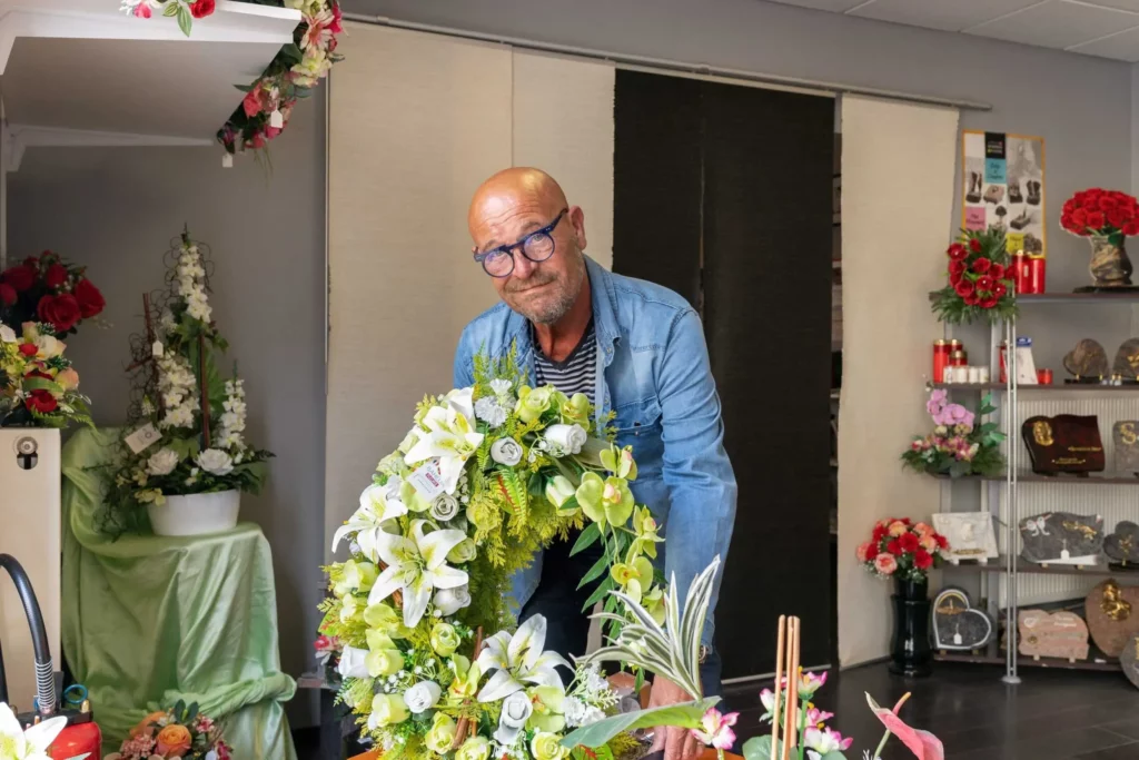 Conseiller funéraire préparant une couronne de fleurs en boutique.