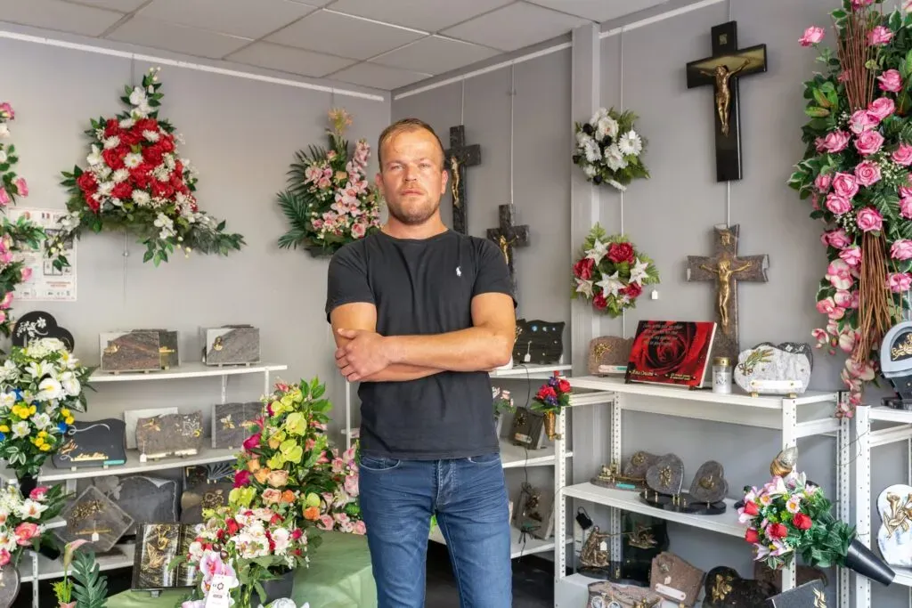 Conseiller en agence devant des plaques et ornements funéraires.