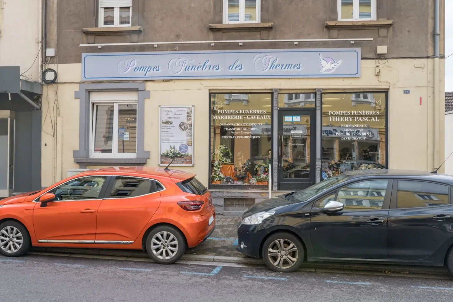 Façade d'une entreprise de pompes funèbres avec véhicules garés devant.