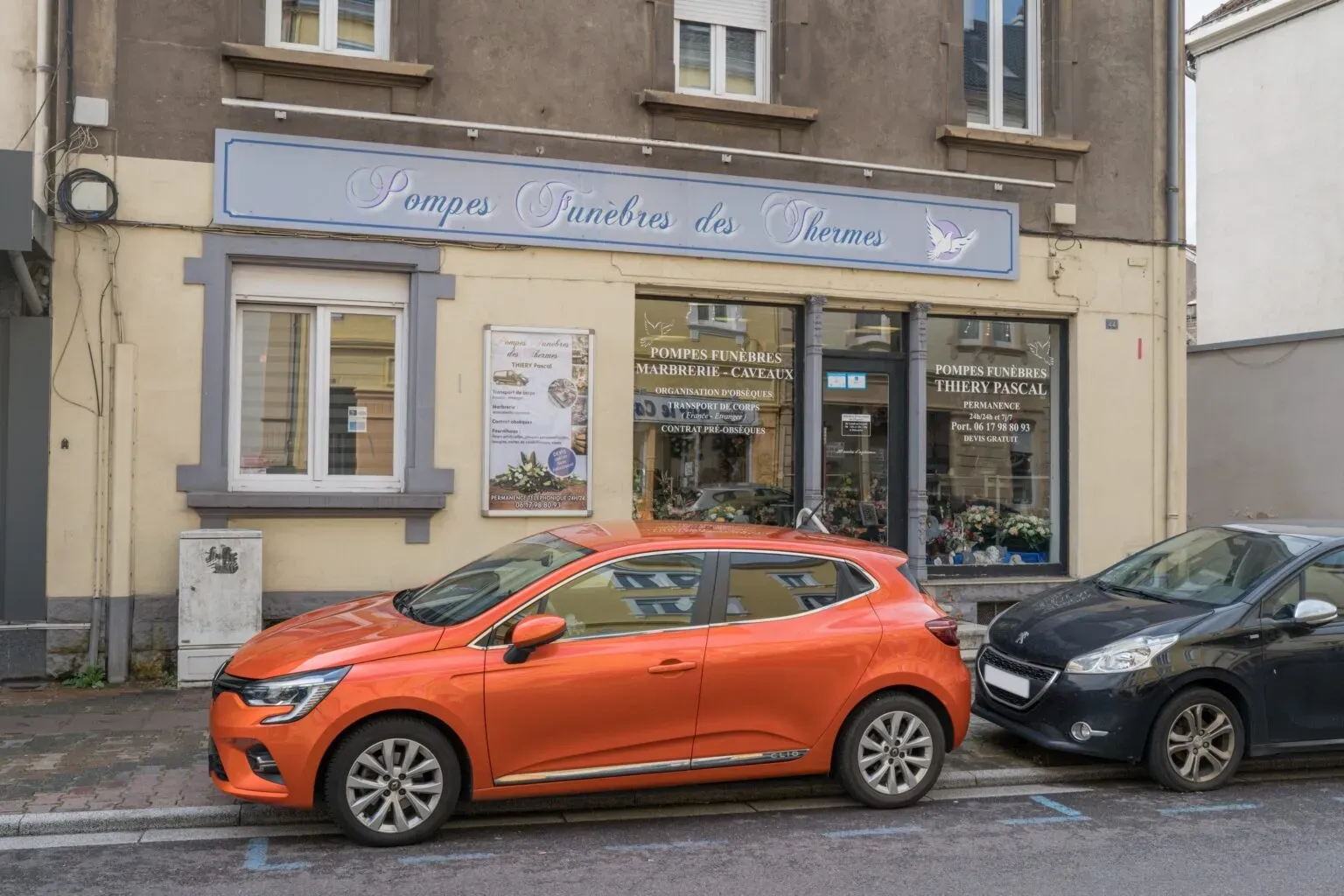 Façade d'un magasin de pompes funèbres avec des véhicules garés devant.