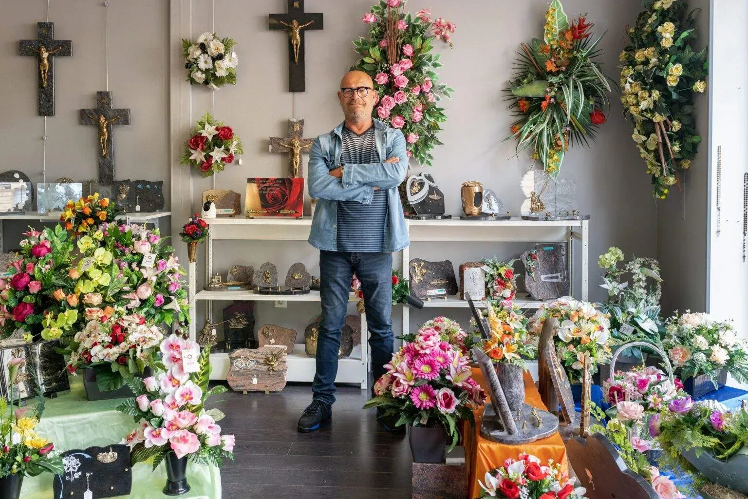 Conseiller funéraire posant au milieu de compositions florales de deuil.